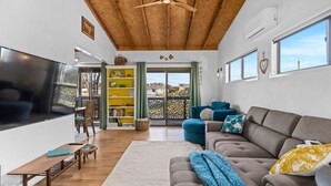 Una sala de estar con sofá, televisión y estantería.
