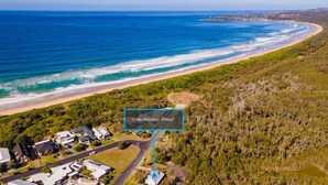 Vista aérea de una zona costera con playa, casas y vegetación densa.