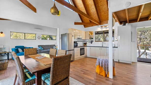 Amplia sala de estar con una mesa de comedor de madera, sillas de mimbre y un sofá azul.