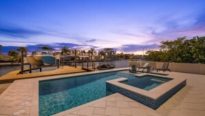 Une piscine avec un jacuzzi, des chaises longues et une vue sur les bateaux et l’eau.