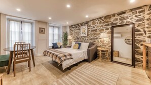 Un dormitorio acogedor con cama, sofá, mesa de comedor y pared de piedra.
