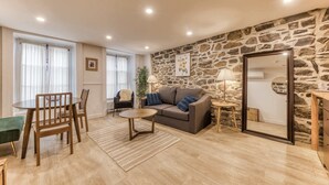 Una sala de estar moderna con una pared de piedra, un sofá, una mesa de centro y una zona de comedor con sillas.