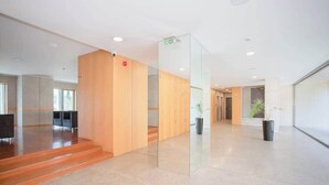 Ein modernes Interieur mit einem Holzerrezeptionstresen, einer Glastrennwand und einer Treppe zu oberen Stockwerken.