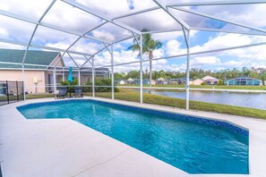A swimming pool with a clear blue water feature, surrounded by a covered area with a metal frame.