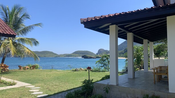Un espacio de estar al aire libre techado, con vistas al mar y las colinas.