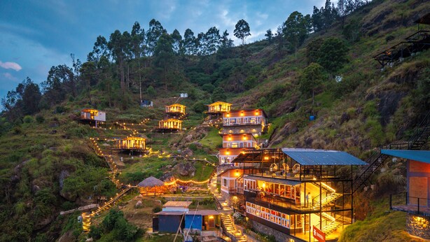 A hillside hotel with multiple buildings connected by staircases, surrounded by lush greenery. - Zostel Plus Poombarai (Kodaikanal) (Kodaikanal)