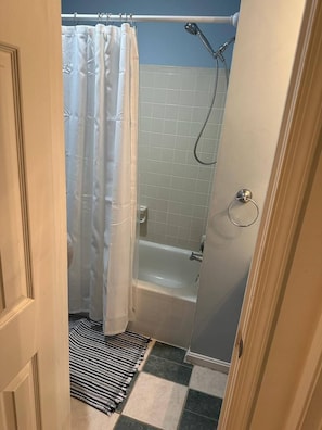 Ein Badezimmer mit Dusche, Badewanne und Fliesenboden.