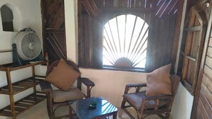 Una habitación acogedora con muebles de madera, una mesita, dos sillas y un ventilador.