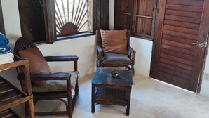 Una habitación con dos sillas de madera, una mesita y una puerta de madera.