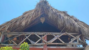 Una estructura de techo de paja con entramado de madera y un elemento decorativo central.