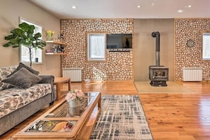 A living room with a sofa, coffee table, and a fireplace with a log wall.