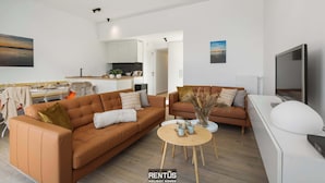Uma sala de estar moderna com dois sofás, uma mesa de centro e uma televisão.