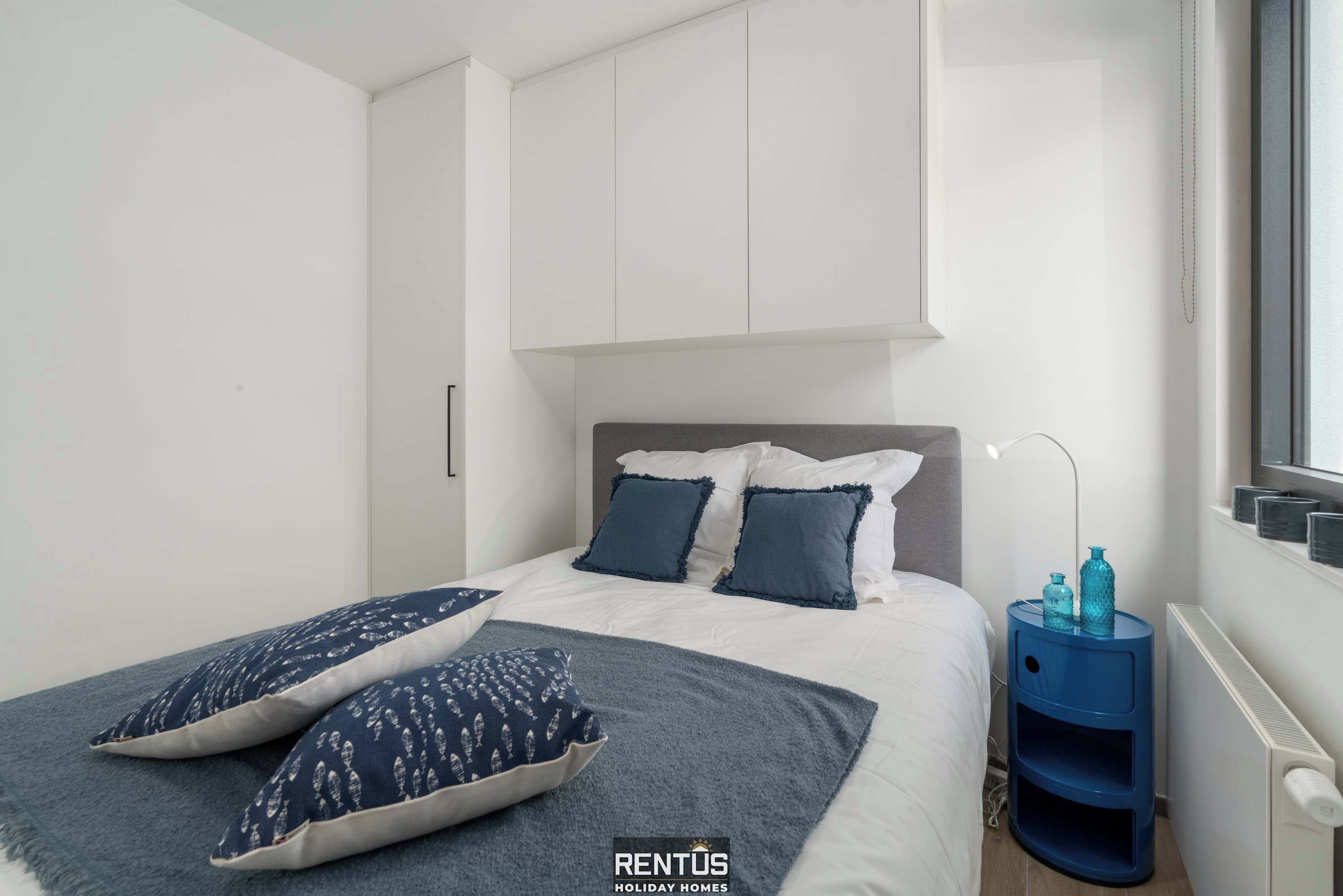 Une chambre à coucher avec un lit, des oreillers, une table de chevet et un radiateur.