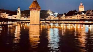 A nighttime view of a historic city with a prominent tower and a bridge reflecting on the water. - Chez Marie Lake I Mountains I Fantastic view I Lucerne  (Beckenried)