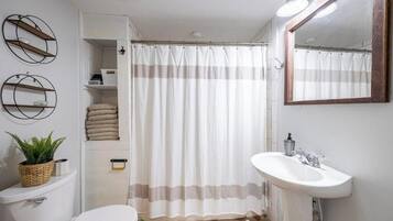 Een badkamer met toilet, wastafel en douchegordijn.