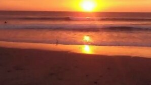 Un coucher de soleil sur une plage, avec des vagues.
