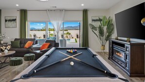 A pool table in a modern living room with a view of mountains and a pool. - Luxury Desert Hot Springs 4BR/3BA Vacation Home /Private Pool & Mountain Views (Desert Hot Springs)
