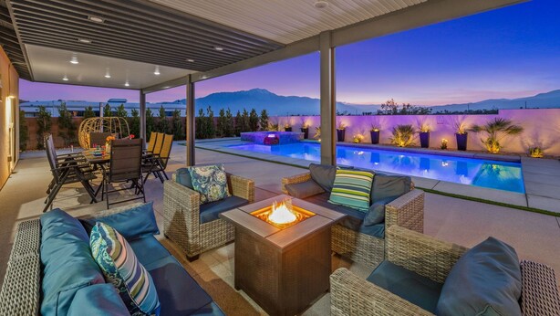 Un espacio al aire libre techado con piscina, muebles de mimbre y una chimenea.
