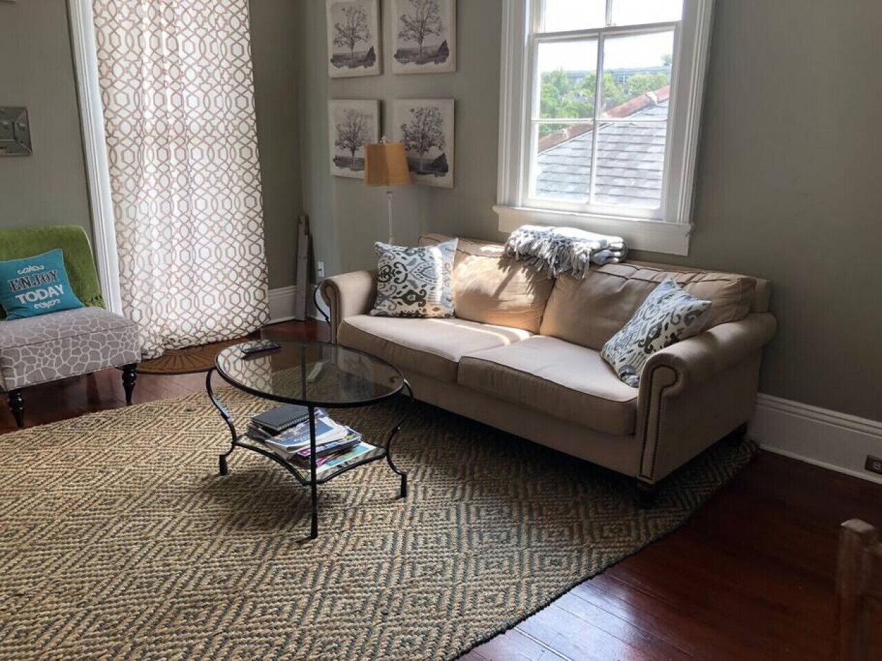 A living room with a beige sofa, patterned rug, and a glass coffee table.