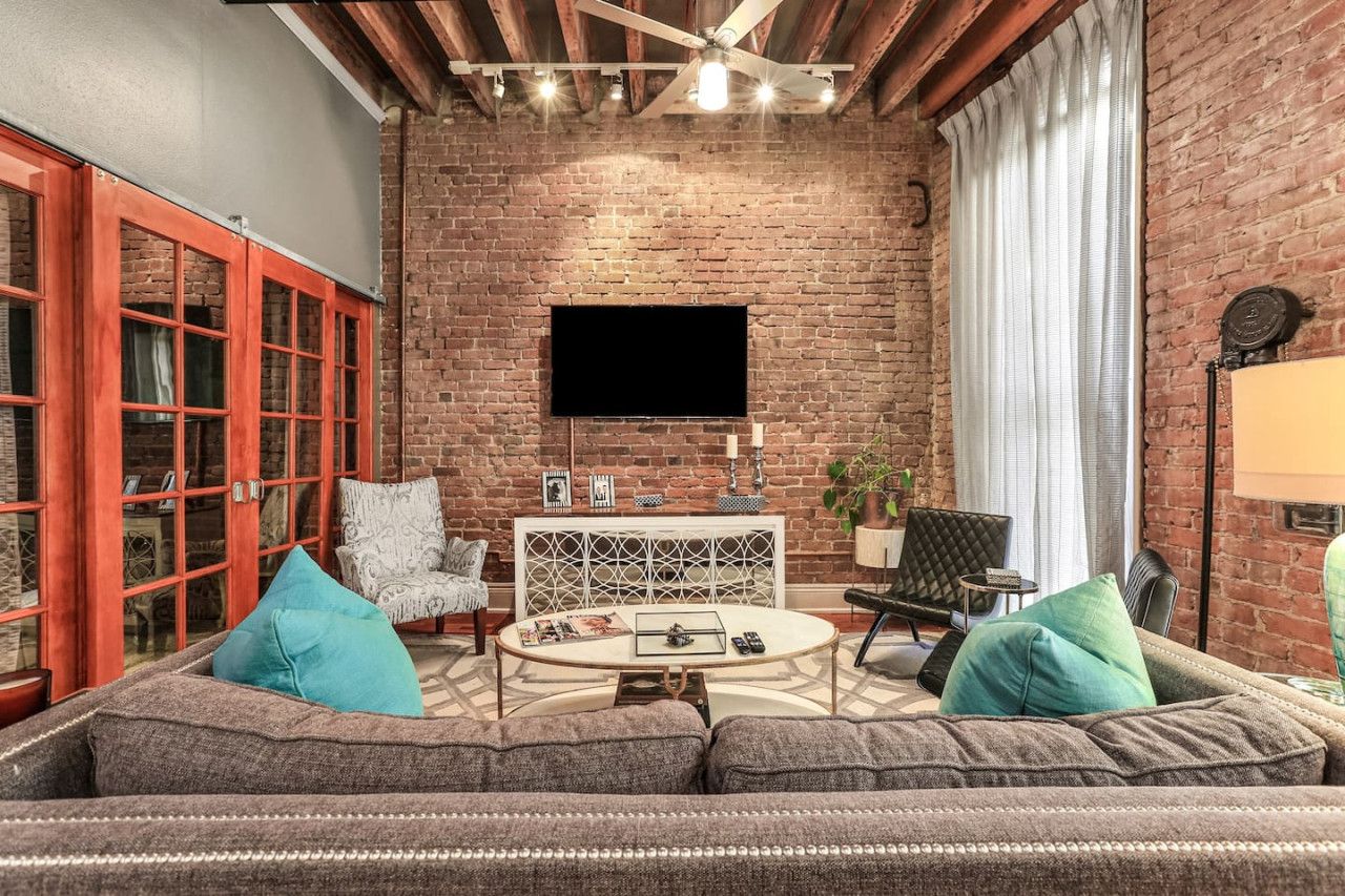 Een gezellige woonkamer met een bakstenen muur, een flatscreen televisie, een ronde salontafel en comfortabele zithoek.