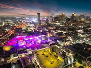 An aerial view of a cityscape at night with illuminated buildings, a prominent tower, and a brightly lit stadium.