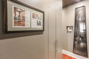 Un article encadré accroché au mur, une porte avec un panneau de verre et une grande œuvre d’art encadrée.