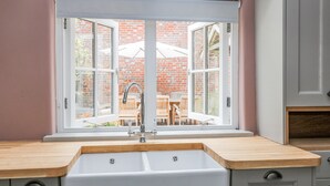 A kitchen with a large window, a sink, and wooden countertops. - The Old Bakehouse (Marlborough)