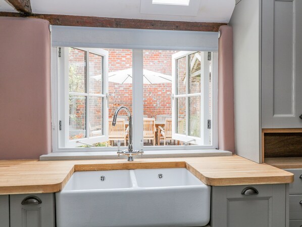 A kitchen with a large window, a sink, and wooden countertops.