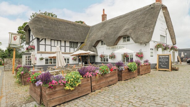 A traditional thatched-roof building with outdoor seating and flower planters. - The Old Bakehouse (Marlborough)