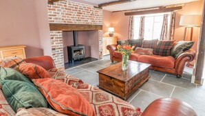 A cozy living room with a brick fireplace, a sofa set, and a coffee table. - The Old Bakehouse (Marlborough)