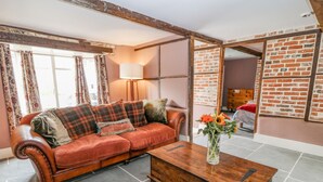 A living room with a sofa, a wooden coffee table, and a vase with flowers. - The Old Bakehouse (Marlborough)