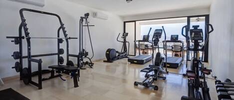 Une salle de sport équipée de divers appareils, notamment un support à squats, un tapis de course et des poids.