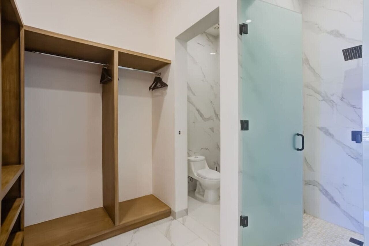 Une salle de bain équipée d’une douche, de toilettes et d’un meuble de rangement en bois.