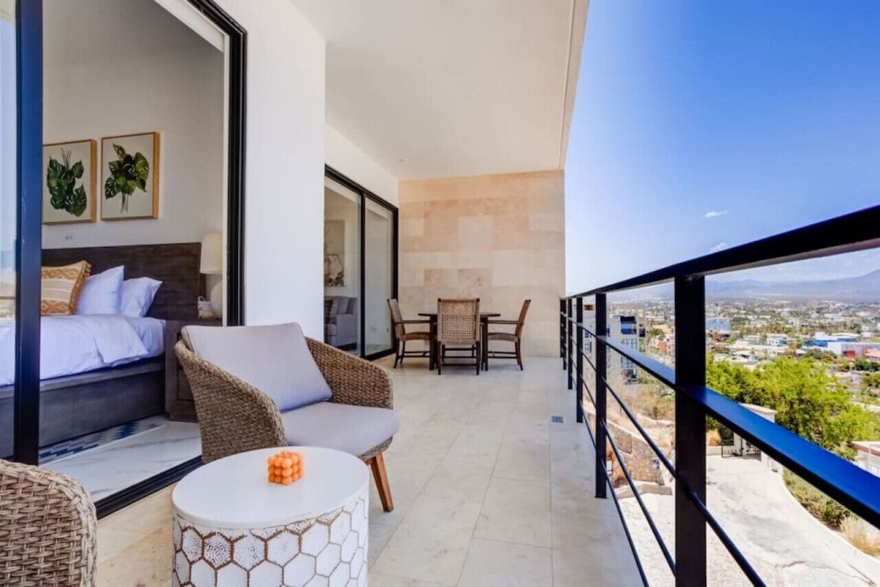 A balcony with a bed, seating area, and dining table.