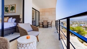 A balcony with a bed, seating area, and dining table. - Elite Ocean View Retreat+ Roof Pool (Cabo San Lucas)