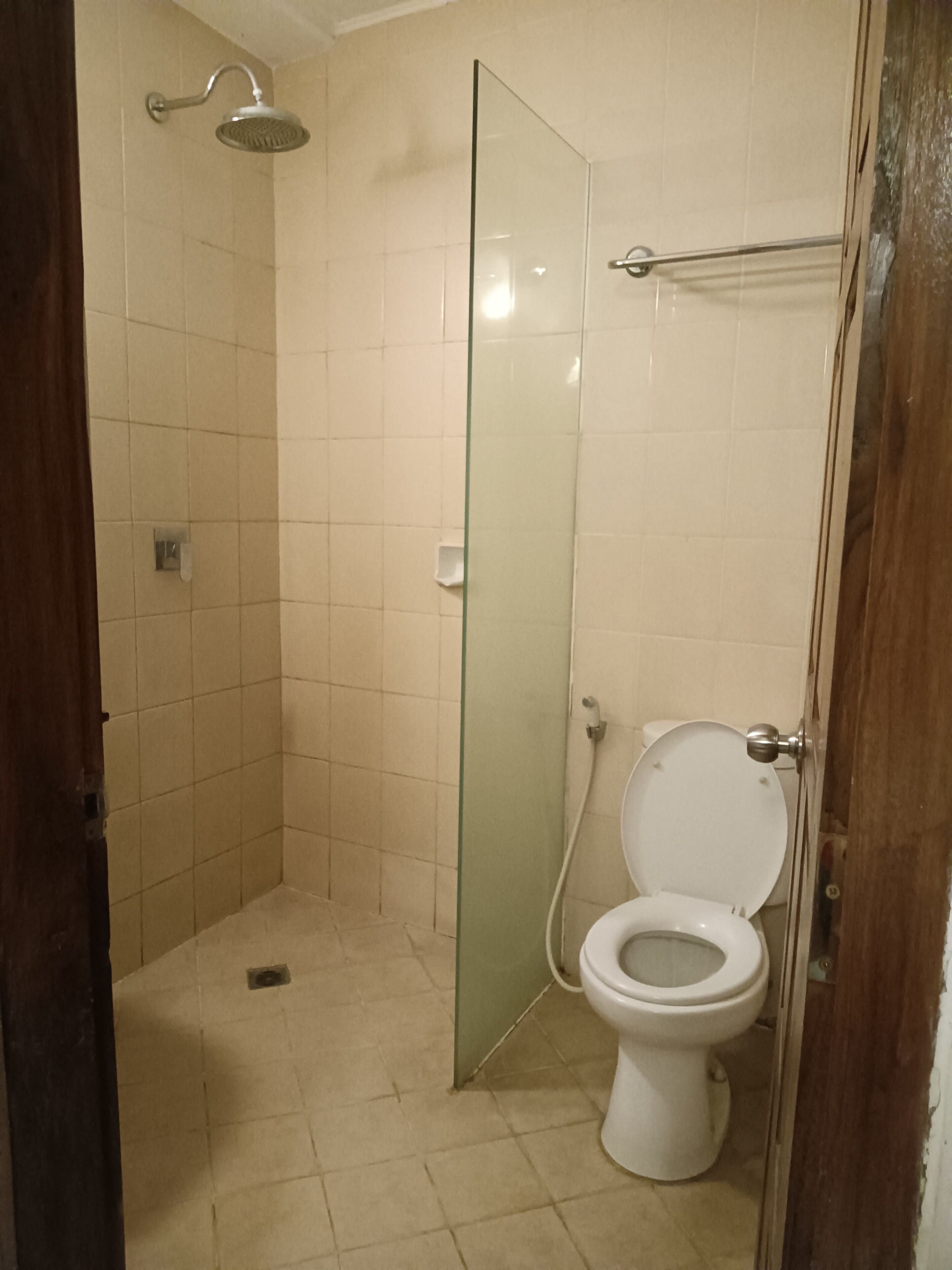 A bathroom with a glass shower enclosure, a toilet, and tiled walls.