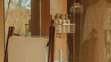 Une salle de bain avec une douche à parois de verre, une porte en bois et un porte-serviettes avec des articles de toilette.