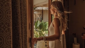 A person opening a door to a room with patterned curtains and a view of greenery outside. - Twinpalms Tented Camp Phuket (Choeng Thale)
