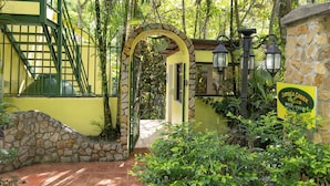 Un ingresso tropicale con arco in pietra, una scala e un cartello con scritto 'Jungle Creek'.
