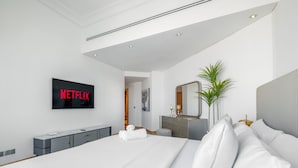 Moderni hotellihuone, jossa on suuri sänky, seinälle asennettu televisio, lipasto ja peili.