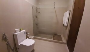 Un baño pequeño con inodoro, cabina de ducha y un perchero para toallas.