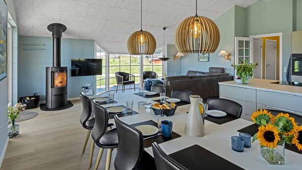 Une cuisine moderne dotée d’une cuisinière intégrée, un coin repas avec des chaises et une table, et un espace de vie avec des canapés et un téléviseur.