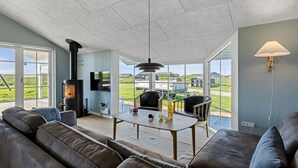 Un salon moderne doté d’une cheminée, de canapés en cuir, d’une table à manger et de grandes fenêtres offrant une vue sur l’extérieur.