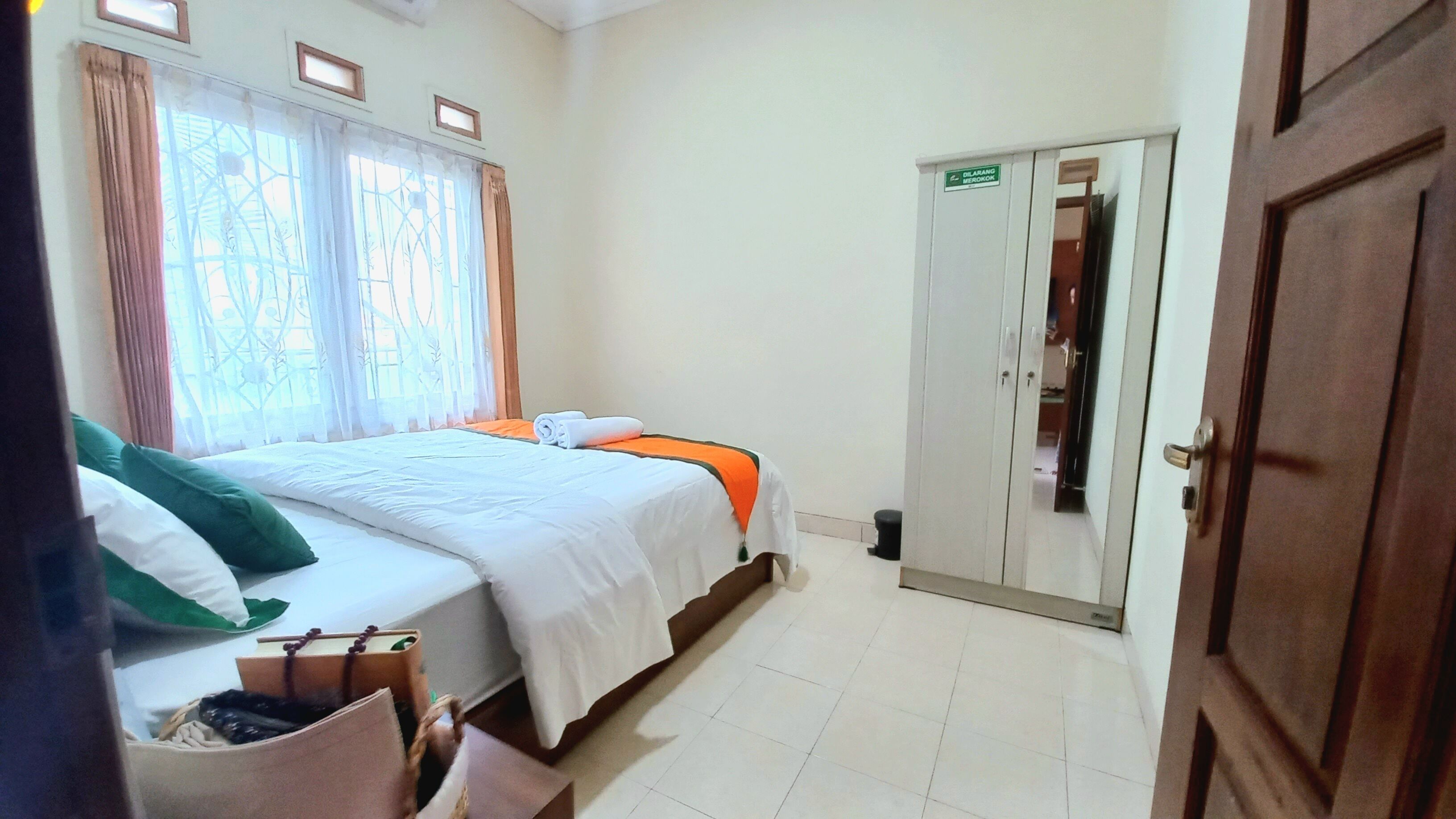A bedroom with a bed, a wardrobe, and a window with curtains.