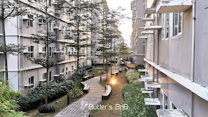 A residential building with multiple balconies, a central pathway, and surrounding greenery.