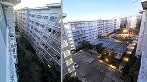 A high-rise residential building with multiple balconies and a parking area.