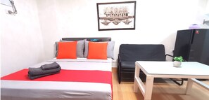 A hotel room with a bed, a desk, a chair, a TV, and a framed picture on the wall.