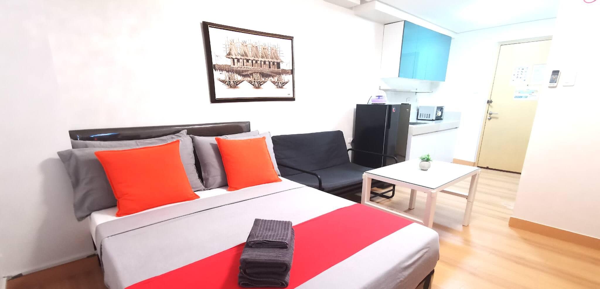 Une chambre d’hôtel équipée d’un lit, d’un bureau, d’une chaise, d’une télévision et d’un coin cuisine.