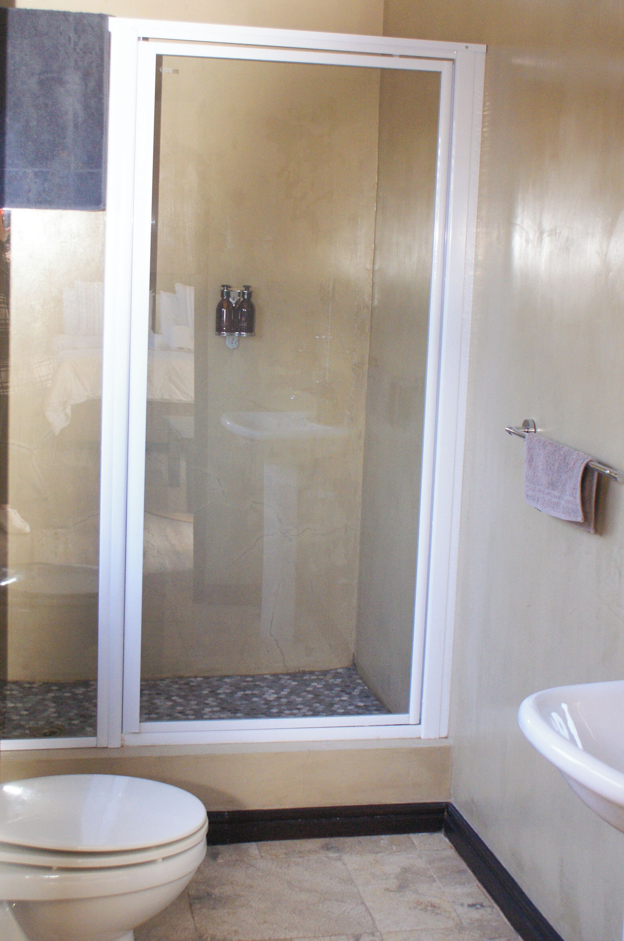 Een badkamer met douchecabine, toilet en wastafel.