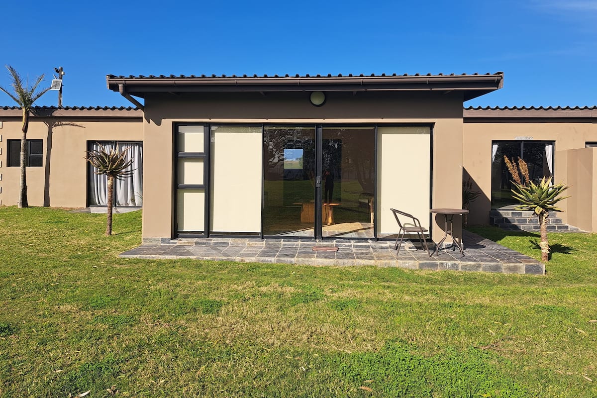 A modern house with a patio, large sliding glass doors, and a small garden area.